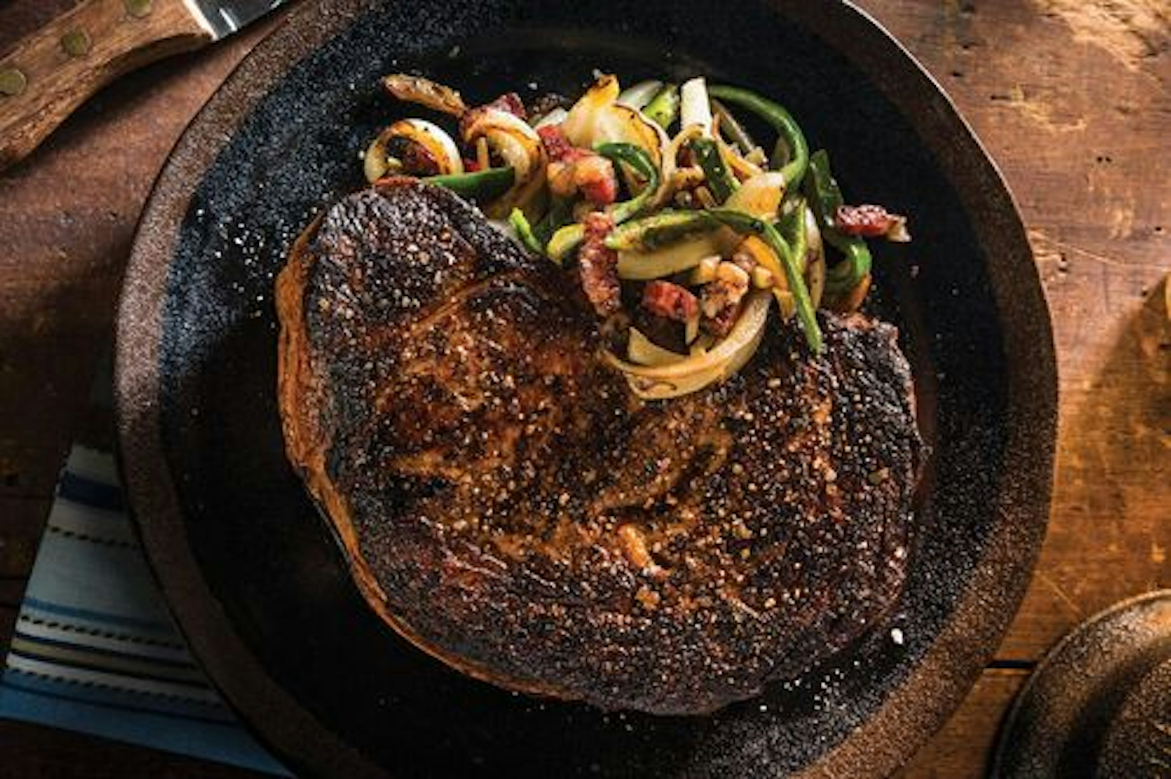 Cast Iron Charred Ribeye with Bacon, Whiskey Onions and Hot Peppers